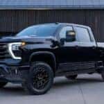 A black 2024 Chevy Silverado 2500 HD High Country Midnight Edition is shown parked on a driveway.
