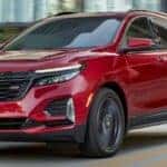 A red 2024 Chevy Equinox drives over a bridge