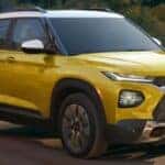 Yellow 2023 Chevy Trailblazer Activ driving down a road near a lake