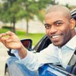 Closeup portrait happy, smiling, young man, buyer sitting in his new blue car showing keys isolated outside dealer, dealership lot, office. Personal transportation, auto purchase concept
