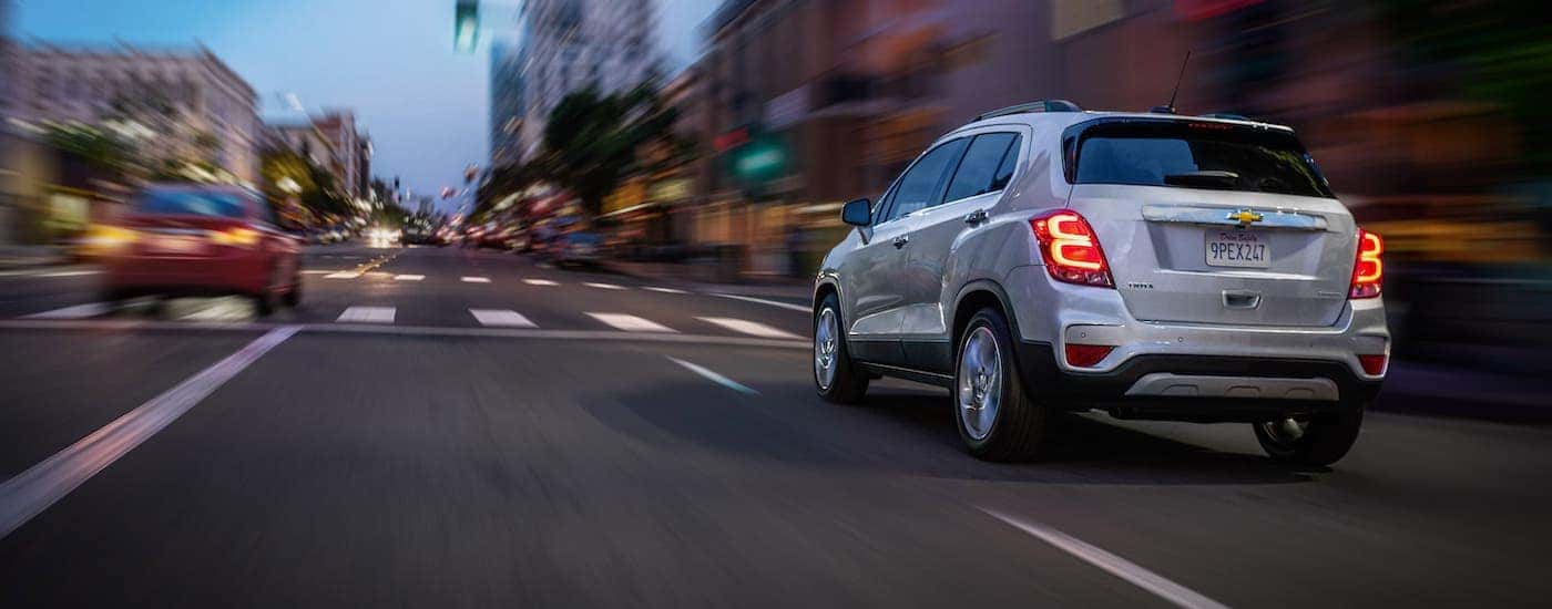 A white 2020 Chevy Trax is leaving a Chevy dealer and driving down a city street outside Buford, GA.