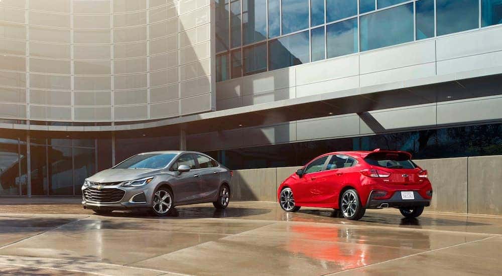 Two of the most popular Chevy Lease deals, the Chevy Cruze, outside a large building