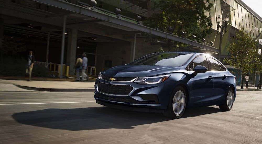 A blue 2017 Chevy Cruze, a popular used Chevrolet car, is driving down a city street.