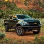 A black lifted 2018 Chevy Colorado, popular among lifted trucks for sale in Georgia, is parked in front of mountains.