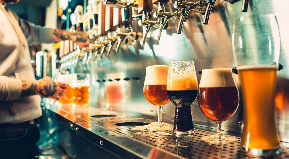 A row of beers in different types of glasses are being poured at an Atlanta, GA bar.