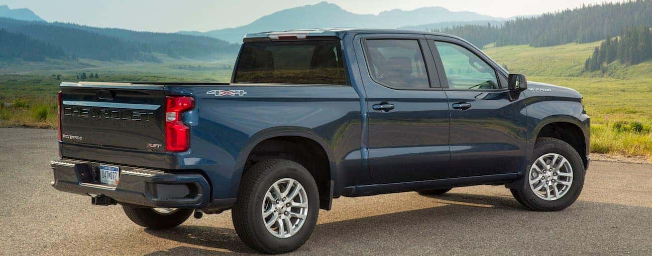 A dark blue 2019 Chevy Silverado 1500 is parked on a hill looking over mountains. 
