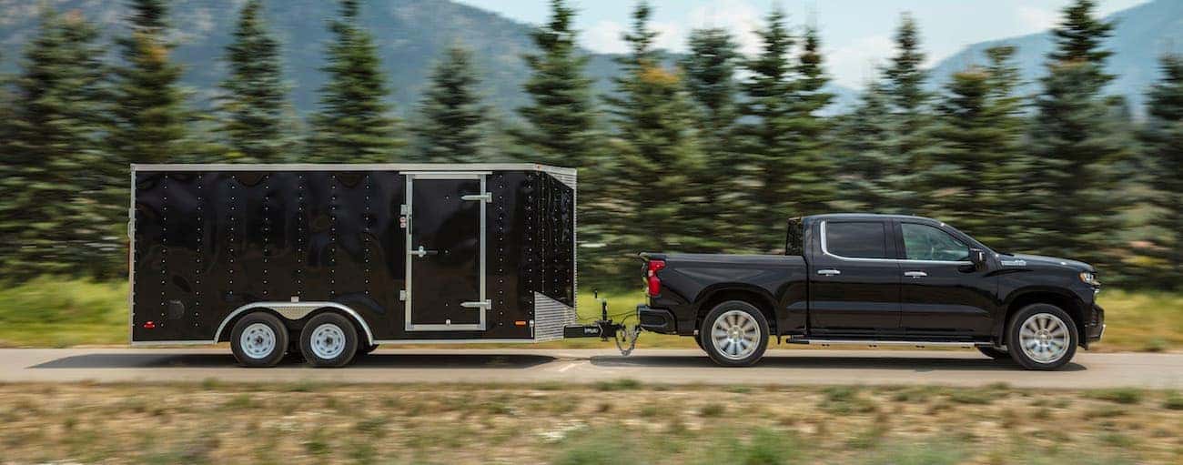 A black 2019 Chevy Silverado 1500, which wins when comparing the 2019 Chevy Silverado 1500 vs 2019 Ford F-150, is towing a large trailer. 