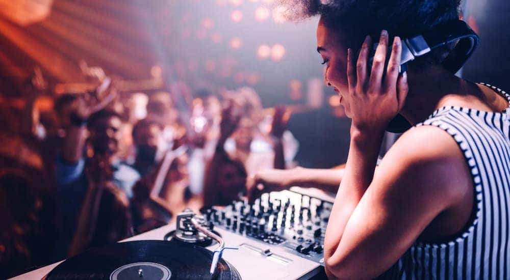 A DJ is playing music at a club near Atlanta, GA while people are dancing on a dance floor.