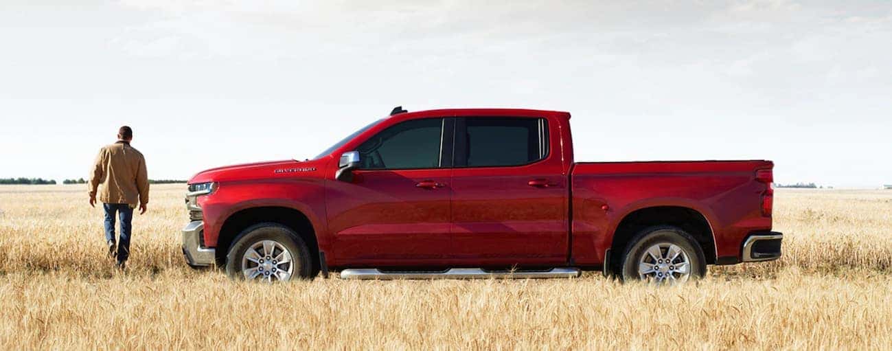 A side view of a red 2020 Chevy Silverado 1500, which wins when comparing the 2020 Chevy Silverado 1500 vs 2020 Ford F-150, is parked in a hay field near Buford, GA.