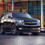 A black 2017 Chevy Tahoe, which is a popular among used SUVs for sale, is parked in front of a glass office building near Buford, GA.