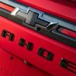 A black Chevy logo on a red 2021 Chevy Tahoe is shown.