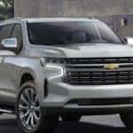 A silver 2021 Chevy Suburban, which is soon to be a popular option among Chevy SUVs, is parked in front of a modern house near Buford, GA.