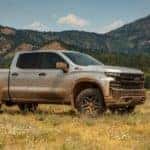 A silver 2020 Chevy Silverado LT TrailBoss from a Chevy dealer near me is covered in mud in a field outside Buford, GA.