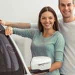 A couple is leaning on a white car with the keys in the man's hand.