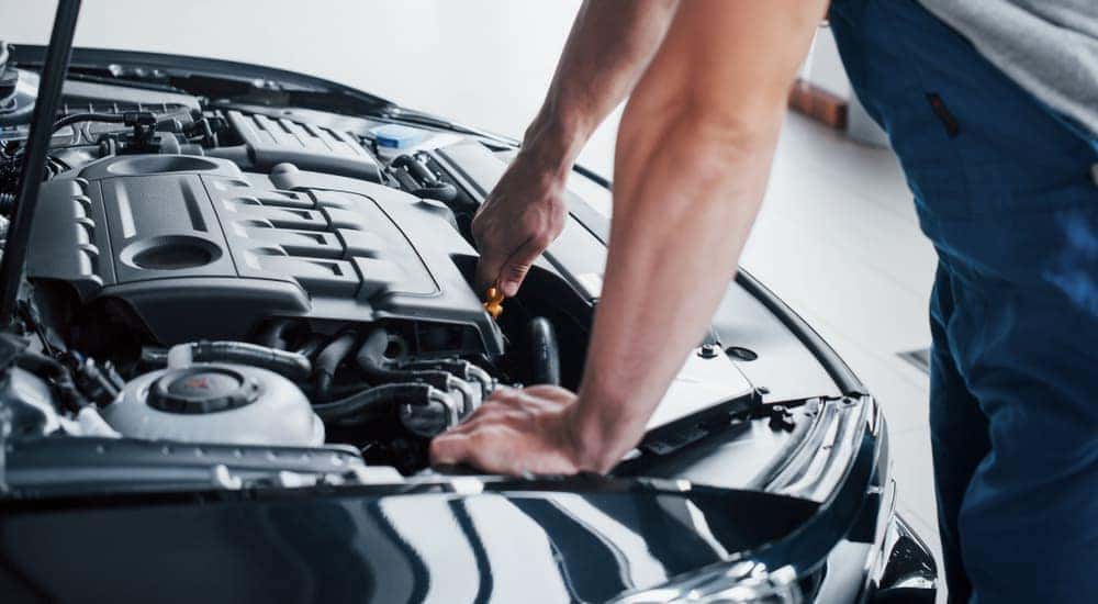 A mechanic is working under the hood of a car.