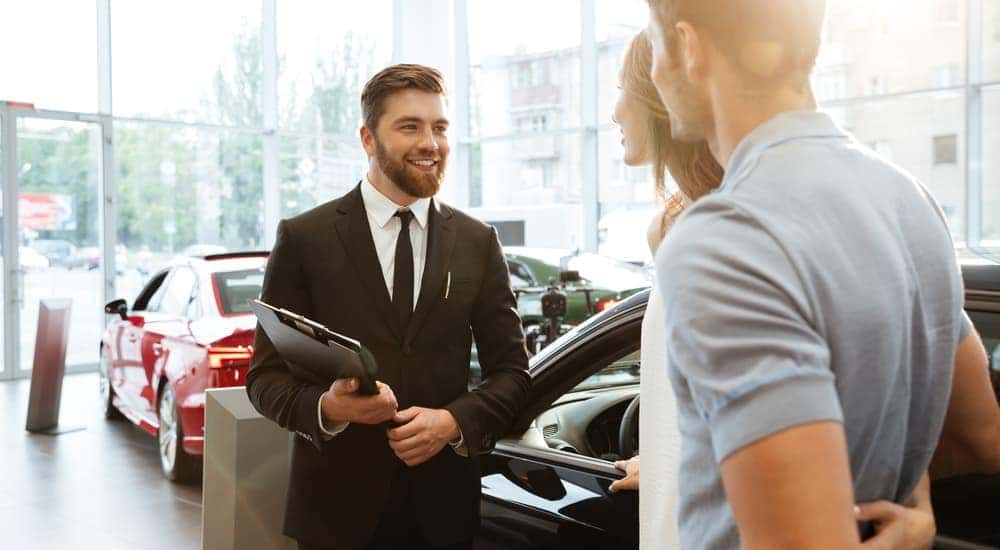 A couple is talking to a salesman at a used car dealership near me in Buford, GA.