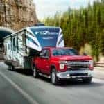 A red 2020 Chevy Silverado 2500HD Z71 is towing a large camper out of a tunnel.