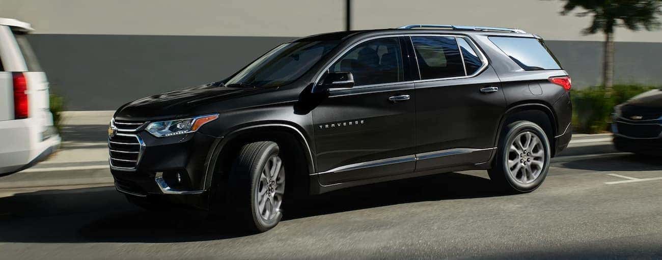 A black 2020 Chevy Traverse is pulling out of a parking spot on a city street near Buford, GA.