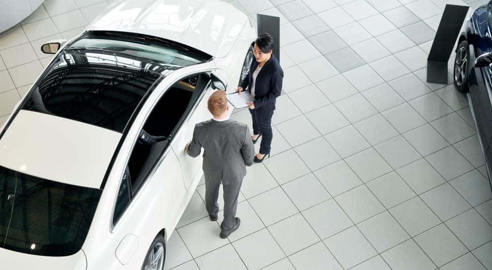 A salesman is talking to a customer next to a white car at an Atlanta Chevy dealer.
