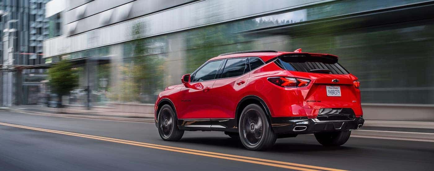 A red 2020 Chevy Blazer, which is popular among Chevy SUV models, is driving on a city street.