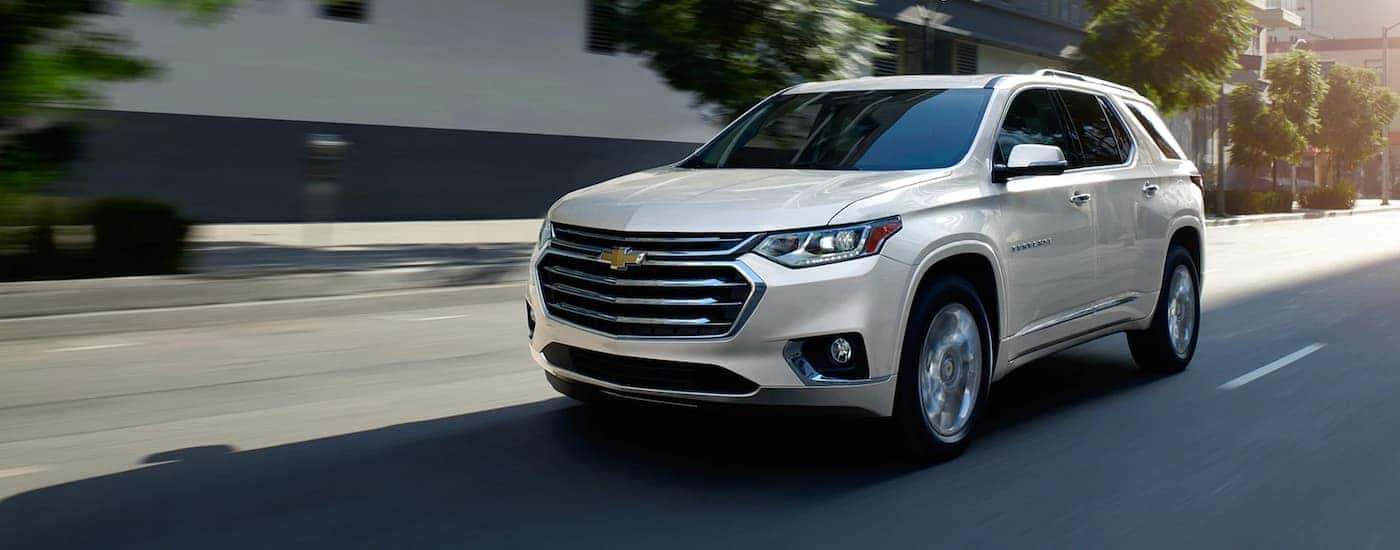 A white 2020 Chevy Traverse is driving on a city street.
