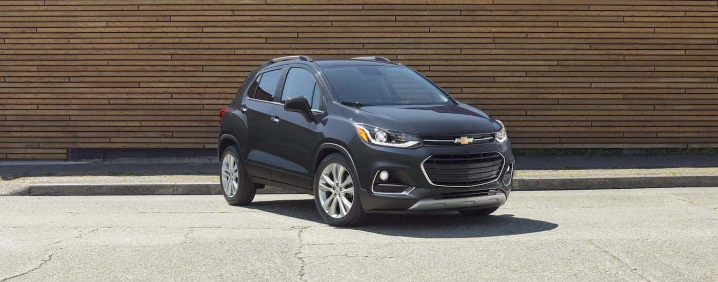 A dark grey 2020 Chevy Trax is parked in front of a wood wall.