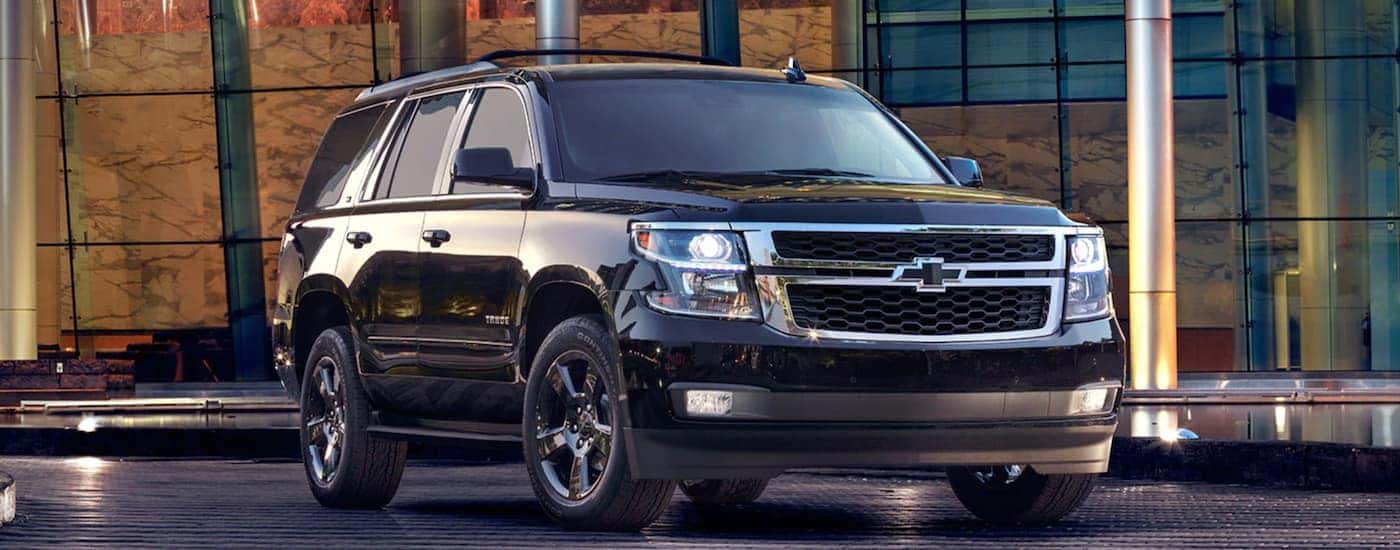 A black 2020 Chevy Tahoe LT Midnight edition is parked in front of a glass building.