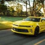 A yellow 2018 Chevy Camaro is driving on a tree-lined road near Buford, GA.
