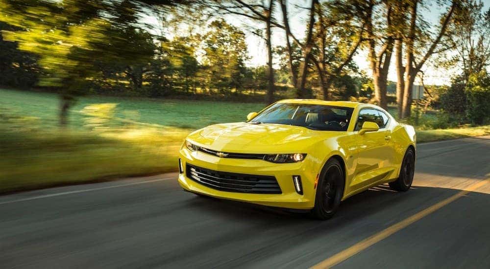 A yellow 2018 Chevy Camaro is driving on a tree-lined road near Buford, GA.