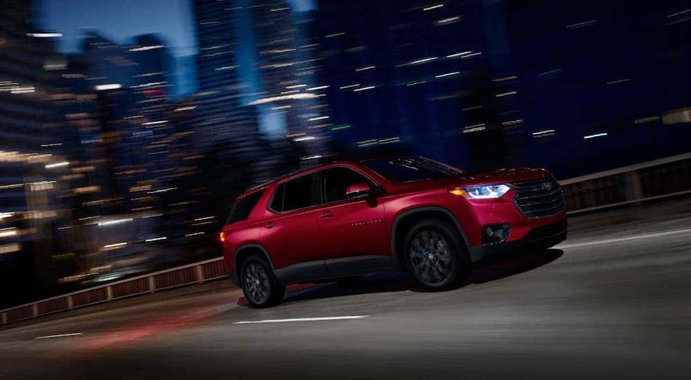 A red 2020 Chevy Traverse RST is driving in a city near Buford, GA, at night.