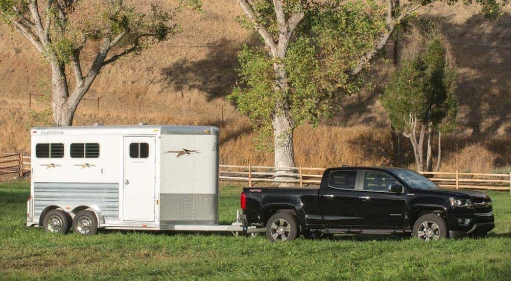 A powerful used Chevy truck, a black 2017 Chevy Colorado, is towing an enclosed trailer near Atlanta, GA.