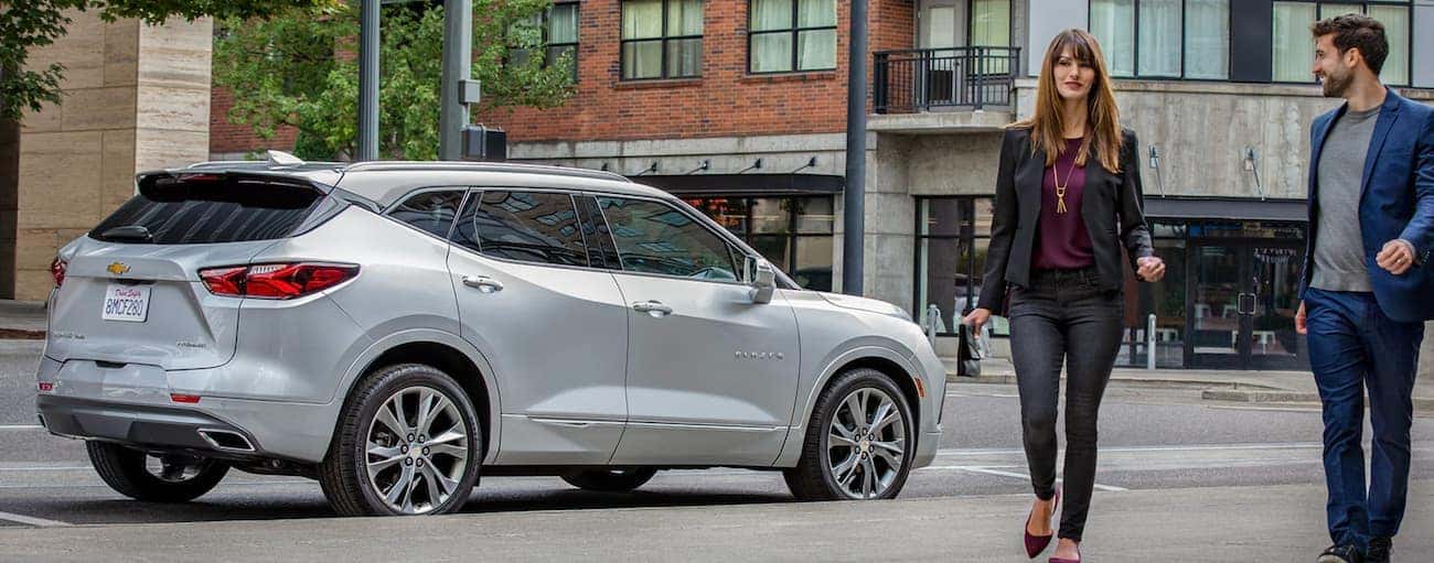 A couple is walking away from a silver 2020 Chevy Blazer on a city street near Buford, GA.