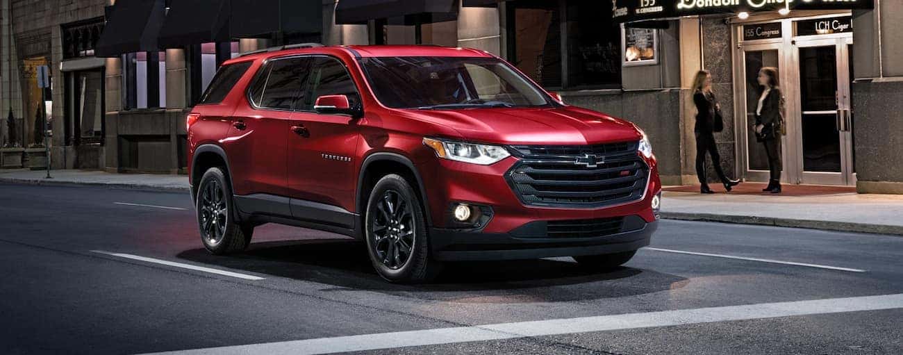 A red 2020 Chevy Traverse is stopped at an intersection on a city street at night after winning the 2020 Chevy Traverse vs 2020 Dodge Durango comparison.