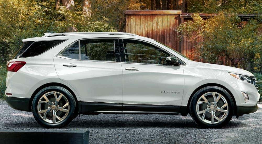 A white 2020 Chevy Equinox is shown from the side in front of a modern wood home.