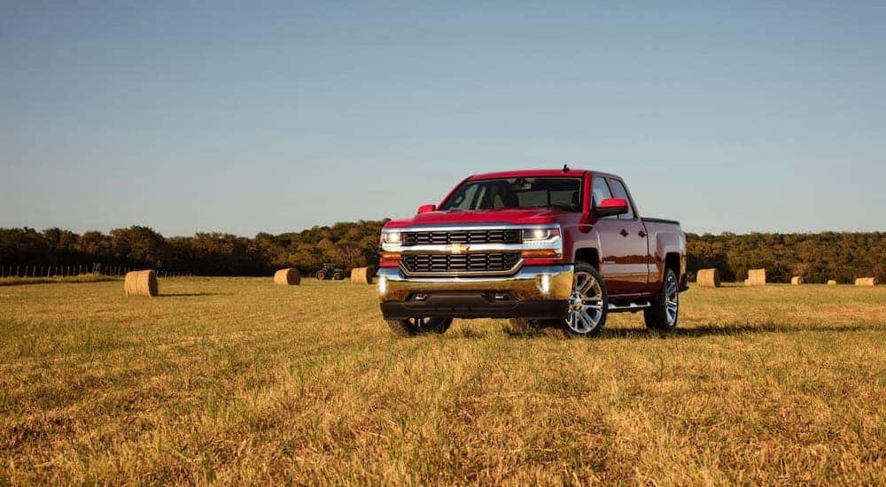 A red 2016 Chevy Silverado LT from a used car dealership near you, is parked in a field.