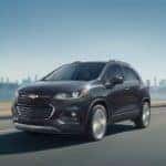 One of the smaller Chevy SUVs, a dark gray 2020 Chevy Trax, is driving away from a city near Buford, GA.