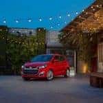A red 2021 Chevy Spark is parked under string lights.