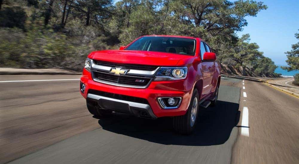 A red 2017 Chevy Colorado Z71 is driving on a road and shown from the front.
