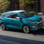 A teal 2021 Chevy Spark is driving on a city street after leaving a Chevrolet dealer in Georgia.