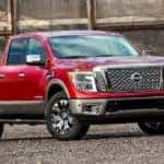 A red 2018 Nissan Titan from an Atlanta Used Truck Dealer is parked in front of a brick building.
