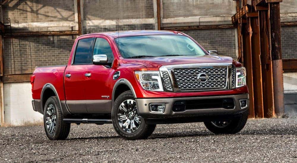 A red 2018 Nissan Titan from an Atlanta Used Truck Dealer is parked in front of a brick building.