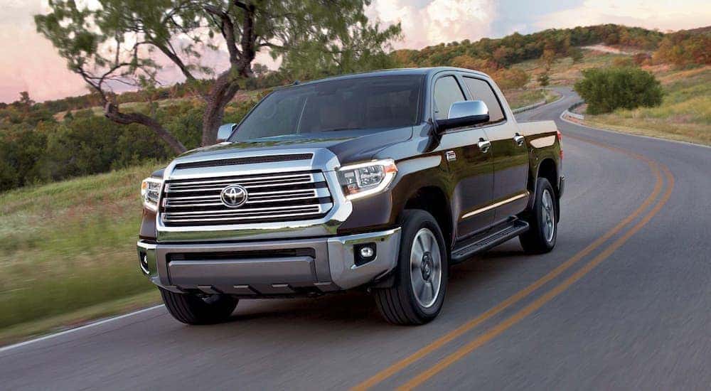 A black 2019 Toyota Tundra is driving on a winding road in front of a tree.