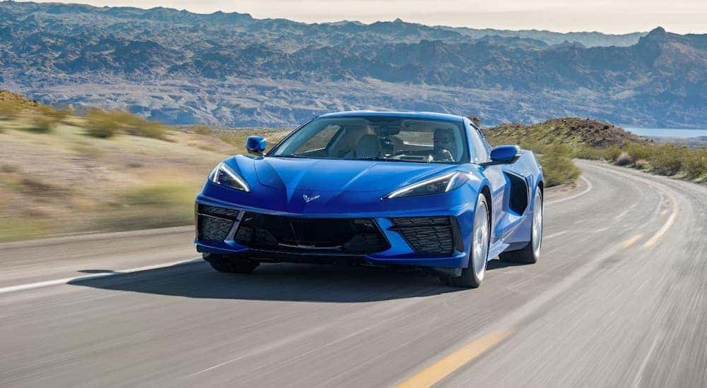A blue 2021 Chevy Corvette Stingray is driving on an empty highway.