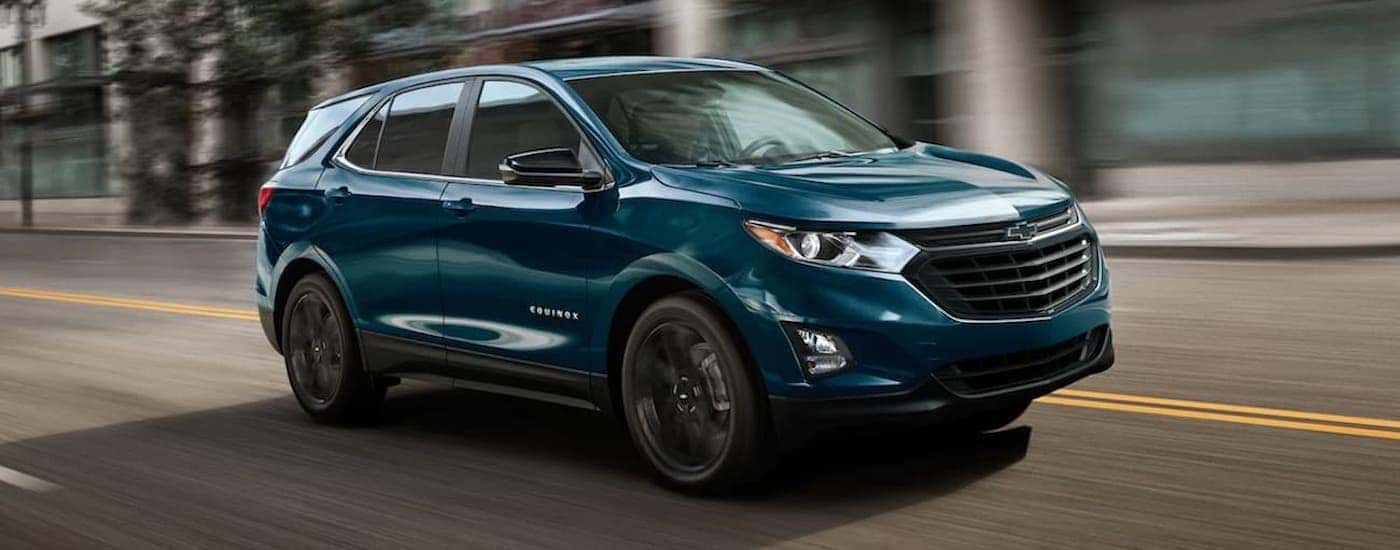 A dark blue 2021 Chevy Equinox is driving on a city street after leaving one of the Chevrolet dealers in Atlanta.