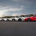 A row of silver different generation Chevy Corvettes are shown from the side with a red 2021 Chevy Corvette in the foreground.