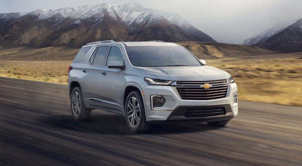A white 2022 Chevy Traverse High Country is driving on a highway.