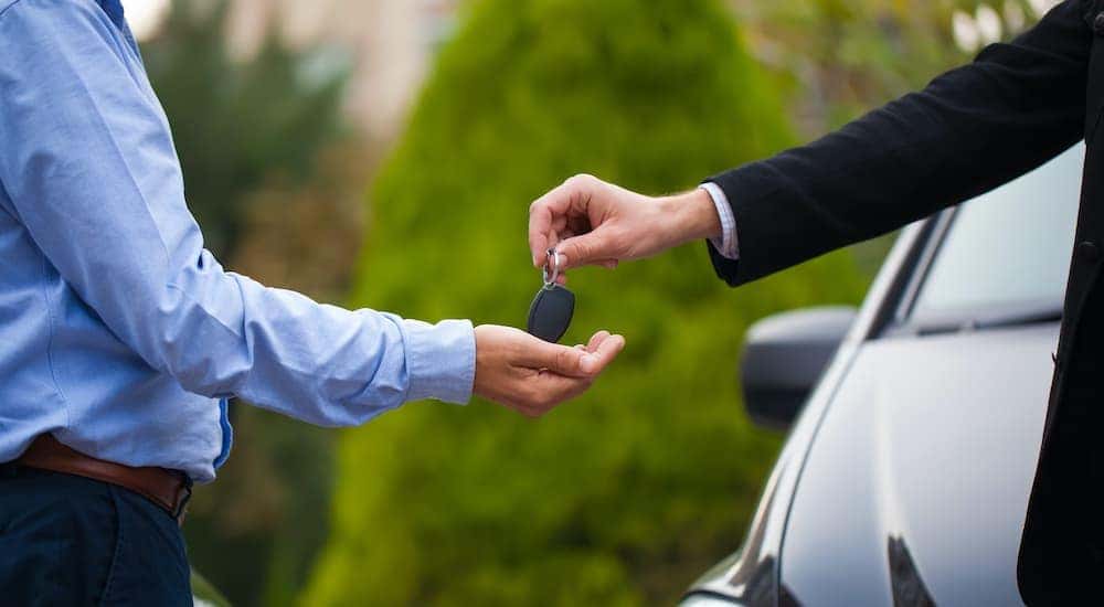 Two sets of hands are shown exchanging car keys.