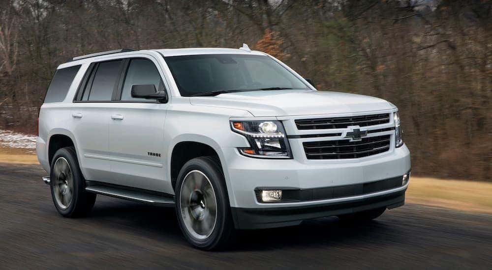 A white 2018 Chevy Tahoe RST is shown from the side driving down a road after leaving an Atlanta used car lot.