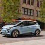 A pale blue 2022 Chevy Bolt EV is shown from the side driving past a fire hydrant.