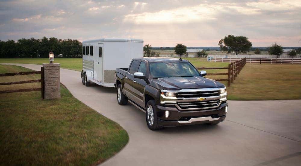 A black 2016 Chevy Silverado 1500 is shown towing a trailer after leaving an Atlanta used Chevy dealer.